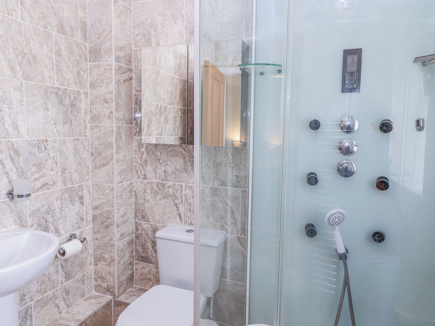 A modern bathroom with a glass-enclosed shower, a toilet, and a sink.
