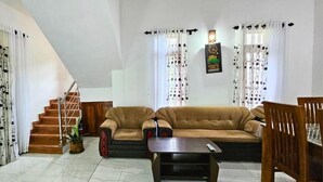 Un salón con un conjunto de sofá, una mesa de centro y una escalera.