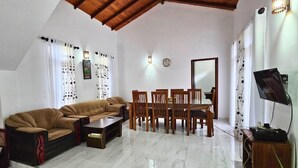 Una sala de estar con sofá, mesa de comedor, sillas y televisor.