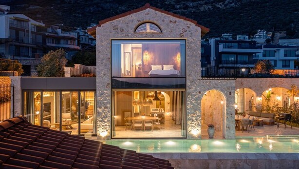 Une villa moderne dotée d’une chambre à coucher entièrement vitrée, d’un coin repas et d’une piscine.