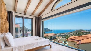 Une chambre avec un grand lit, une vue sur la mer et un balcon.