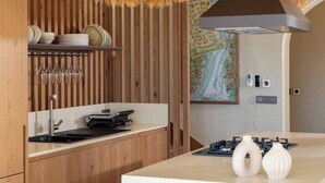 Une cuisine moderne avec des meubles en bois, un plan de travail blanc, des luminaires suspendus en osier et une cuisinière à gaz.