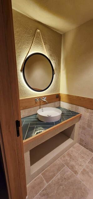 A bathroom with a round mirror, a sink, and a wooden vanity. - Captivating Casa la Calypso (Kaş)