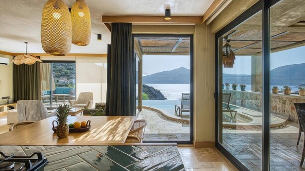 Ein modernes Wohnzimmer mit einem großen Glasfenster, das auf einen Meerblick-Balkon führt.