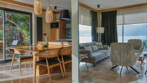 Ein modernes Wohnzimmer mit einer Couch, Sesseln und einem Essbereich mit Tisch und Stühlen.