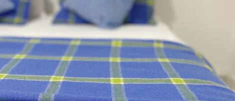A bed with a blue and green plaid blanket and matching pillows.