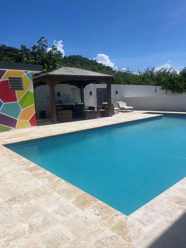 A swimming pool with a covered seating area and a colorful wall. - Sea Breeze Tunnel Hideaway 7 (Quebradillas)