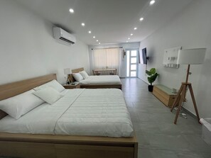 A hotel room with two beds, a desk, a chair, a potted plant, and a lamp. - Sea Breeze Tunnel Hideaway 7 (Quebradillas)