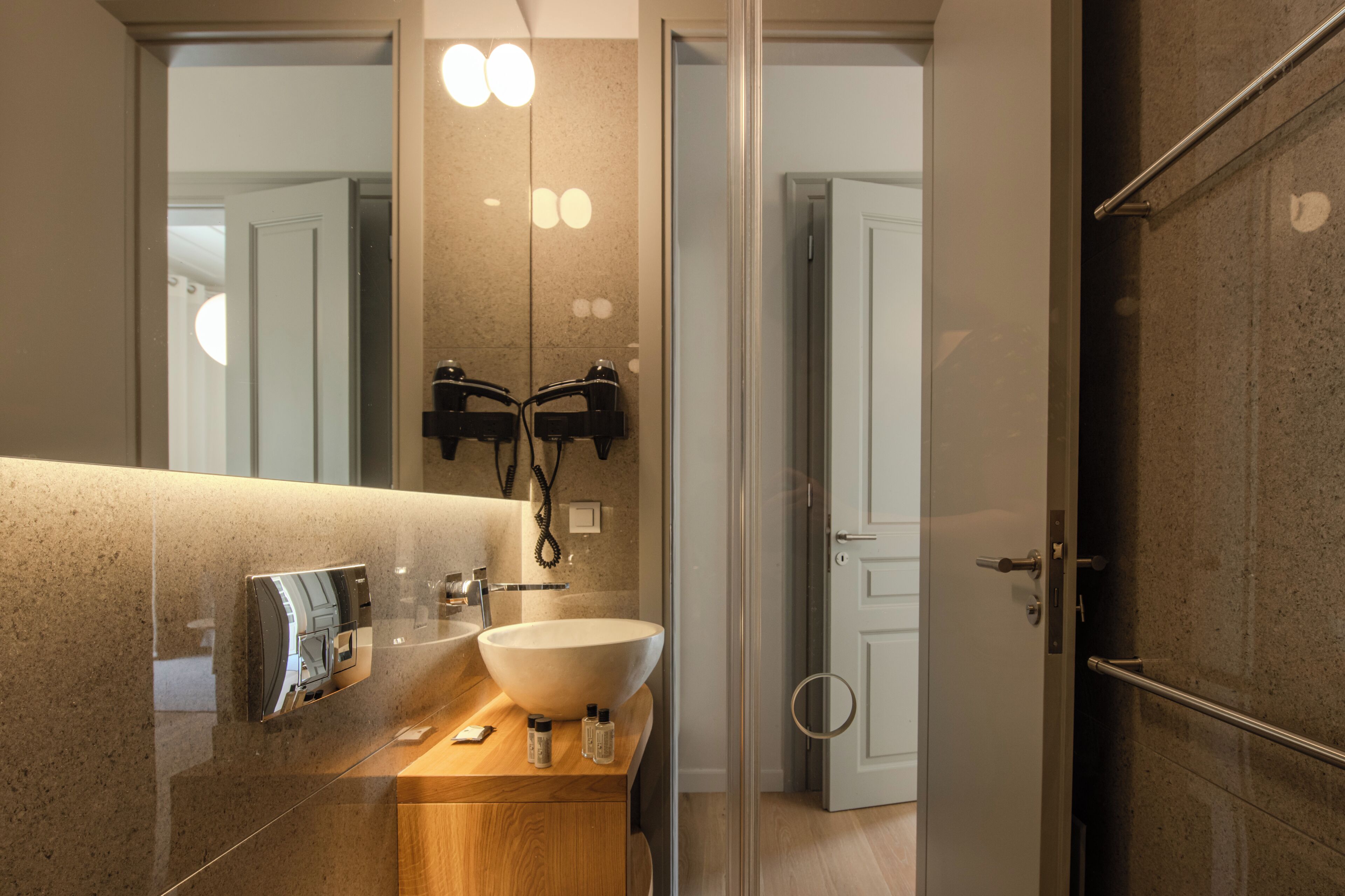 Un baño moderno con un espejo grande, un lavamanos y una zona de ducha.
