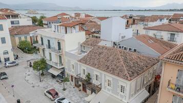 Une ville côtière avec des bâtiments aux toits de tuiles rouges, une rue pavée et des voitures garées.