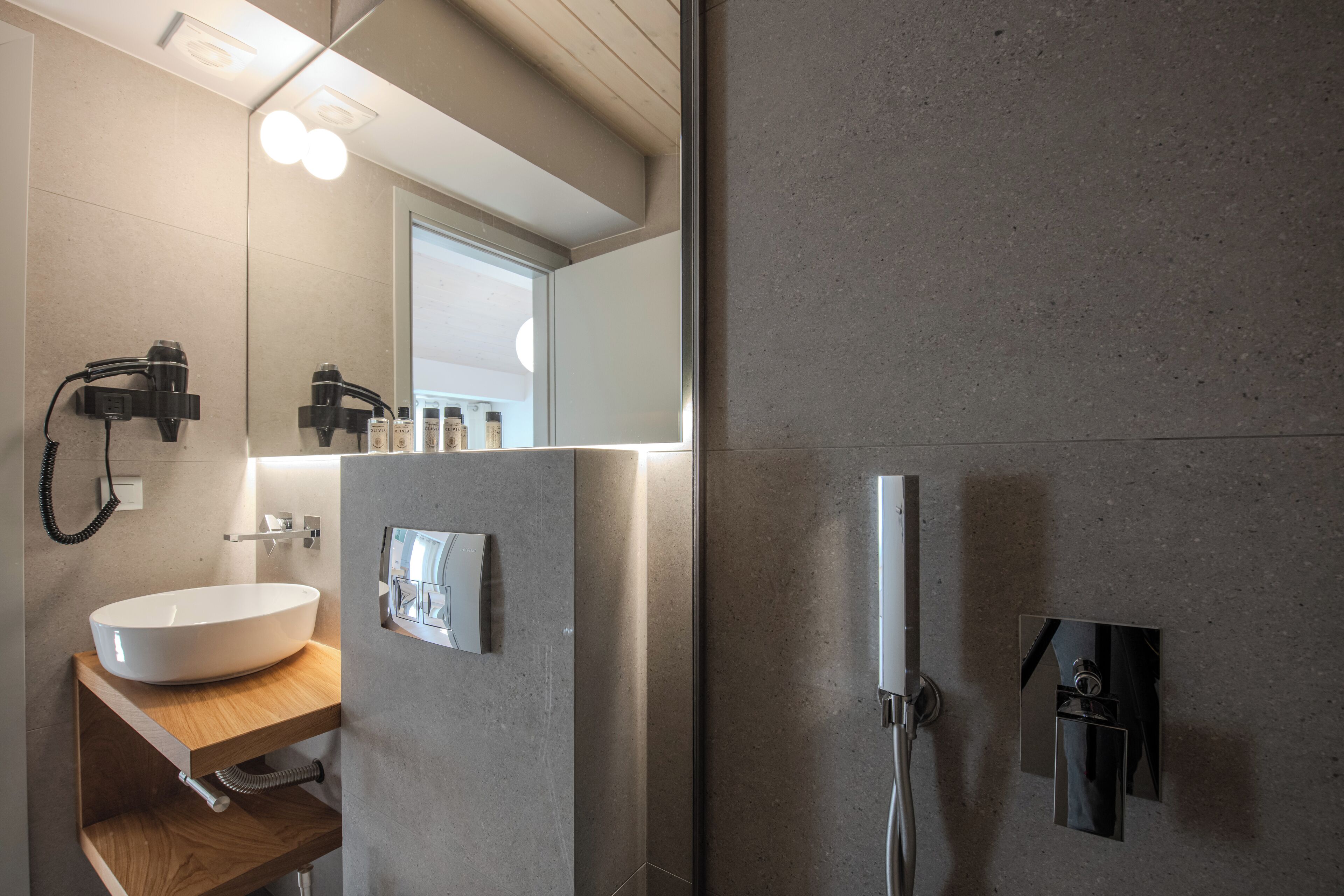 A modern bathroom with a large mirror, a vessel sink, and a handheld showerhead.