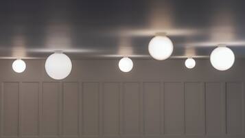 A row of ceiling-mounted spherical light fixtures against a wall with paneling.