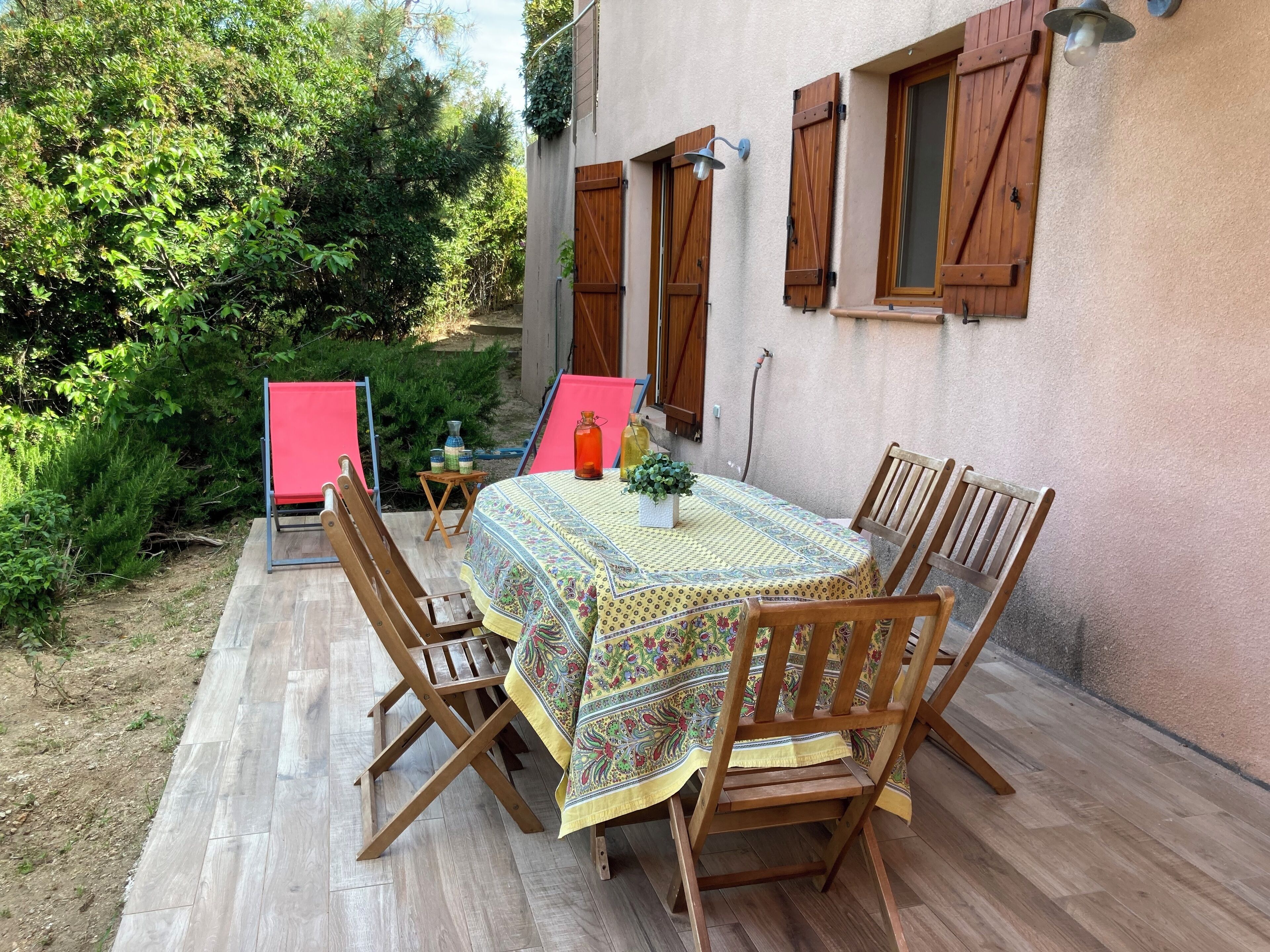 Patio esterno con tavolo apparecchiato per quattro, circondato da sedie in legno.