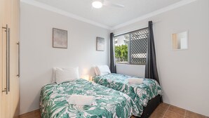 A room with two beds, a window with a view, and a ceiling fan.