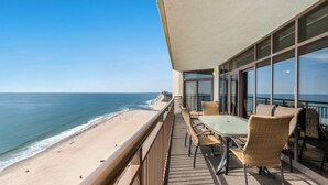 Un balcón con mesa y sillas con vista a la playa.
