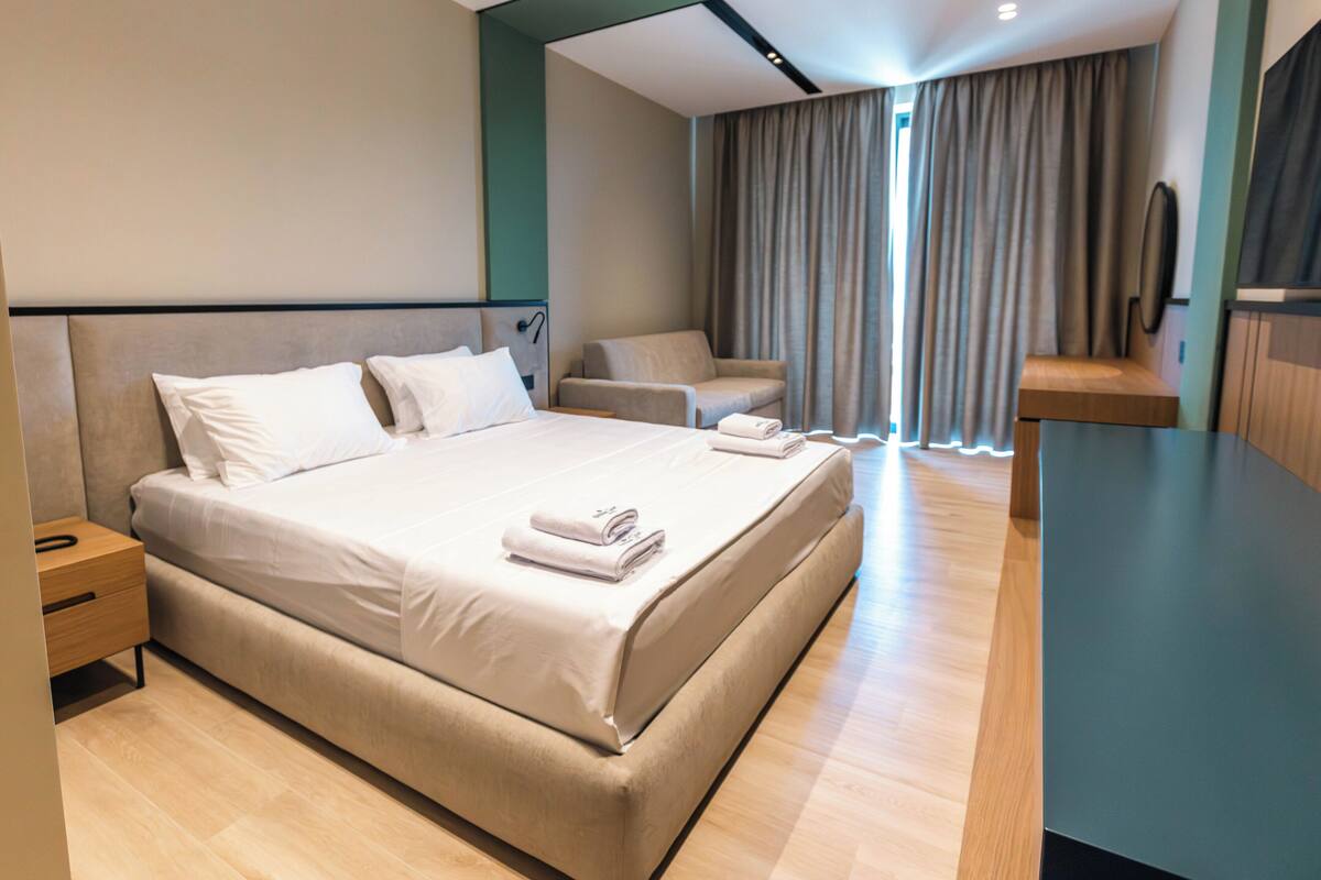 Una habitación de hotel moderna con una cama grande, un rincón de descanso y un televisor de pantalla plana.