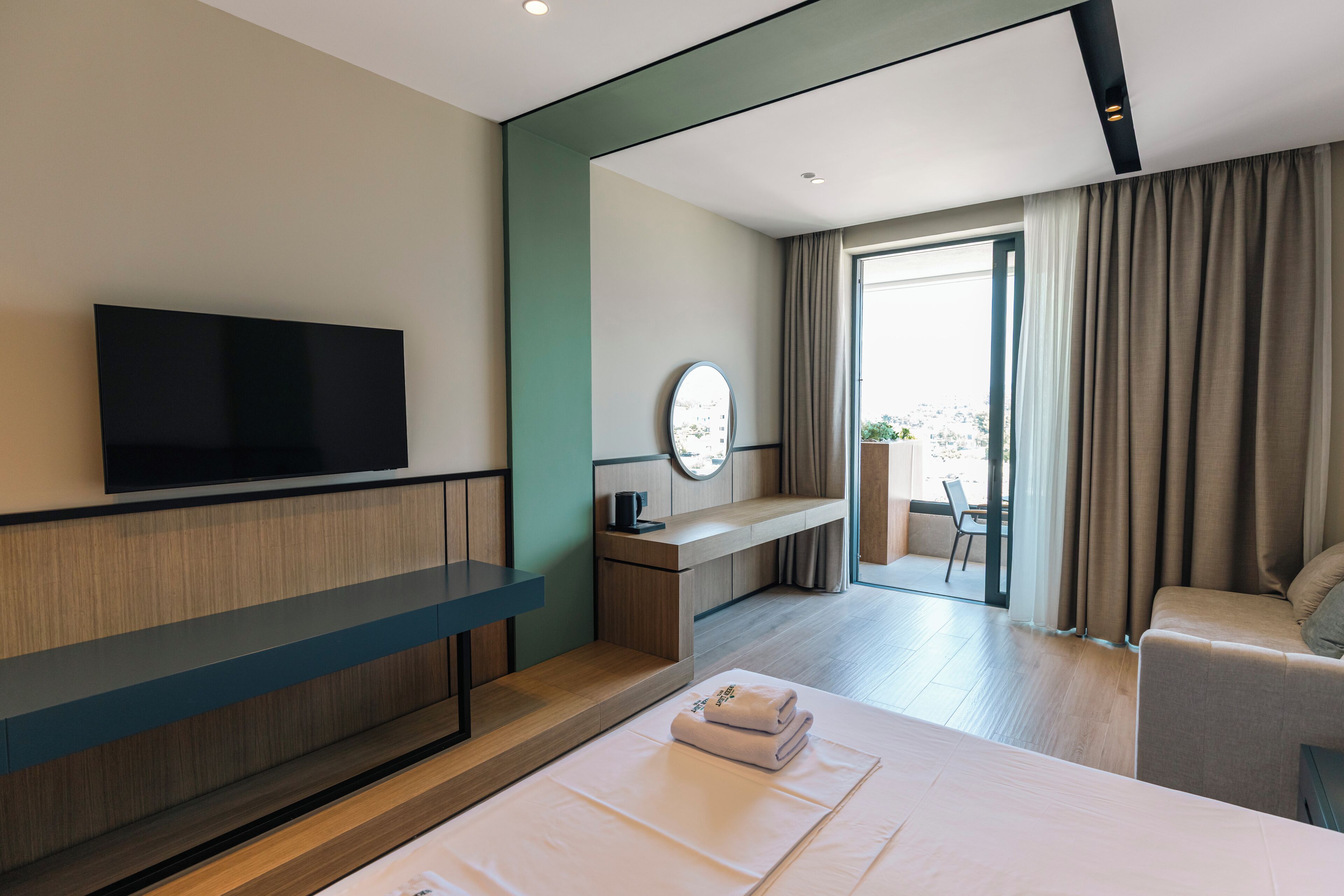 Una habitación de hotel moderna con televisor de pantalla plana, un escritorio, una cama cómoda y vistas al exterior.