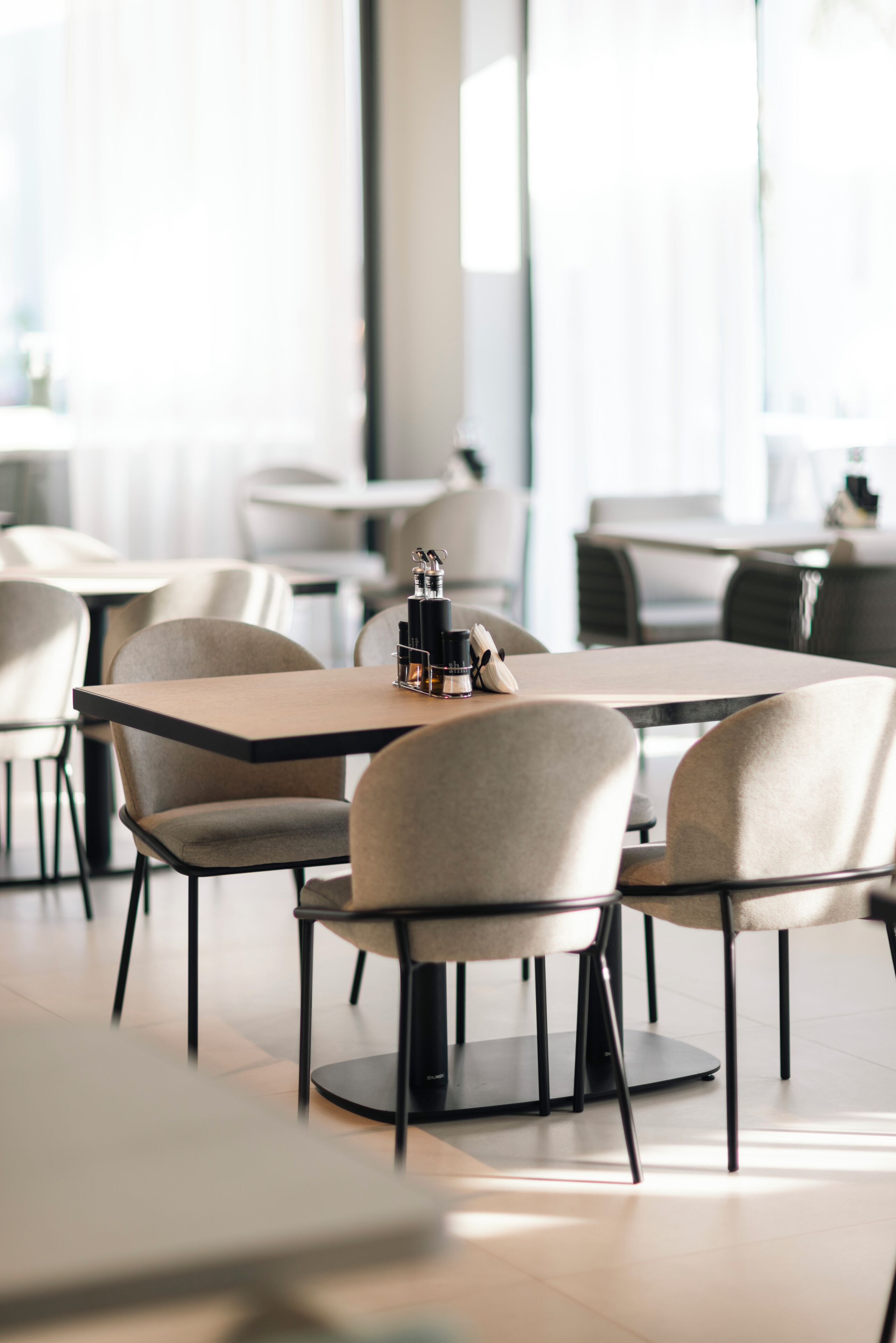 A modern dining area with tables and chairs, large windows, and a clean, minimalist design.