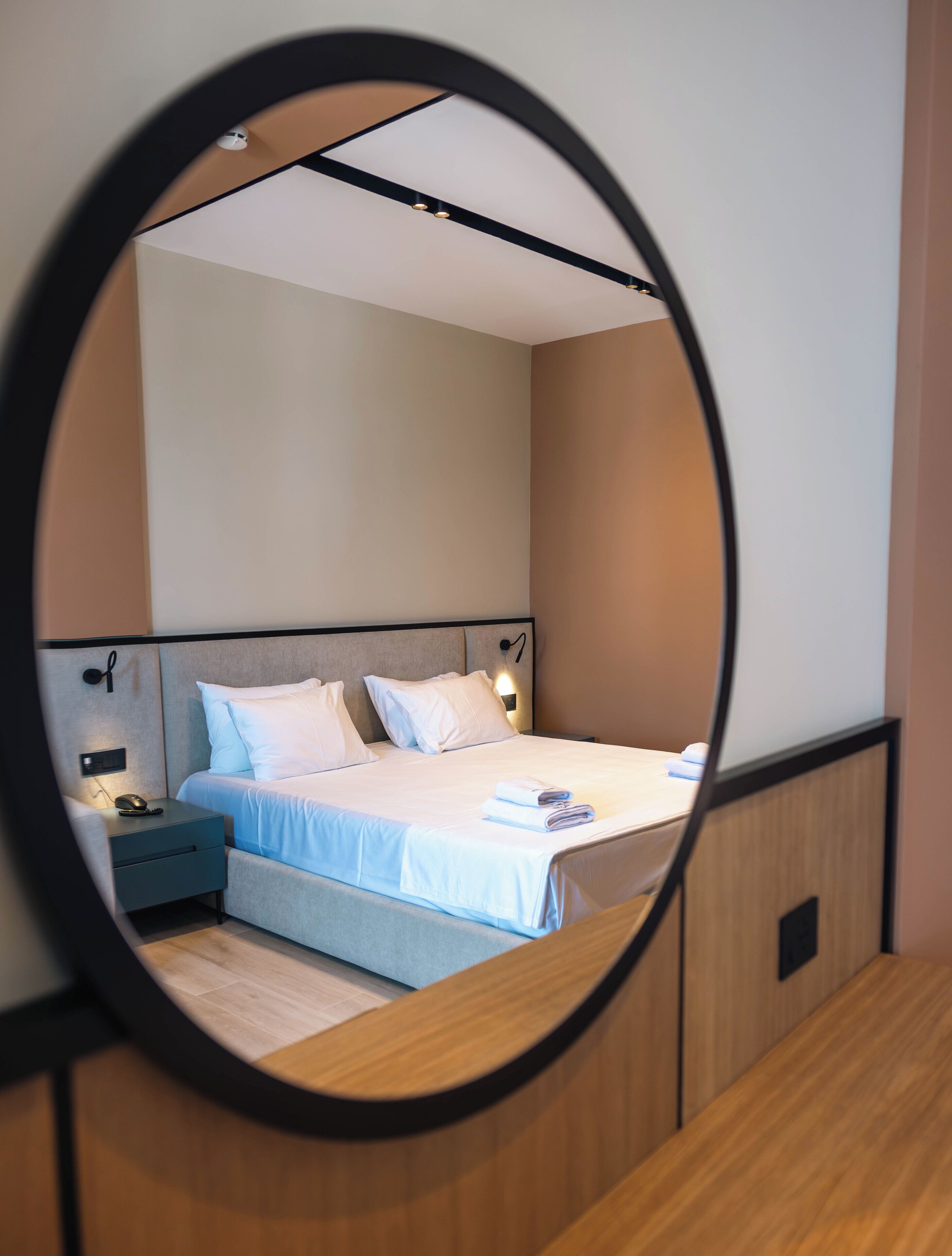 A modern bedroom with a bed, bedside tables, and a mirror.