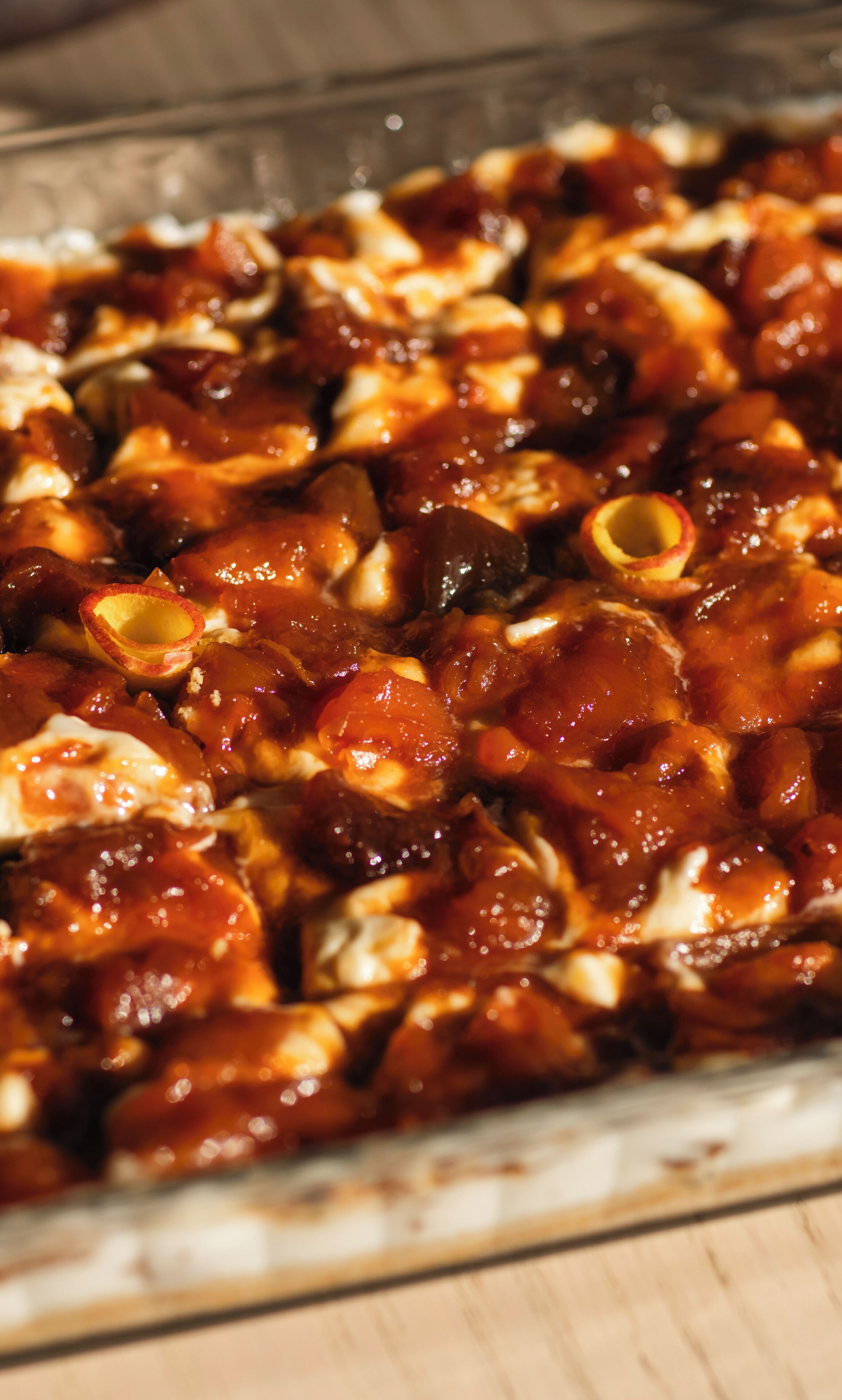 A glass baking dish filled with glazed meat and vegetables.