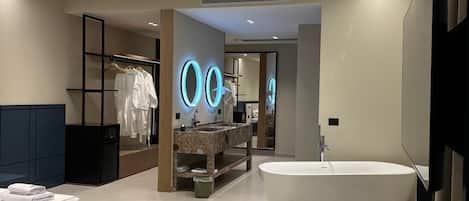 A modern bathroom with a freestanding bathtub, a large mirror, and a vanity with a marble countertop.