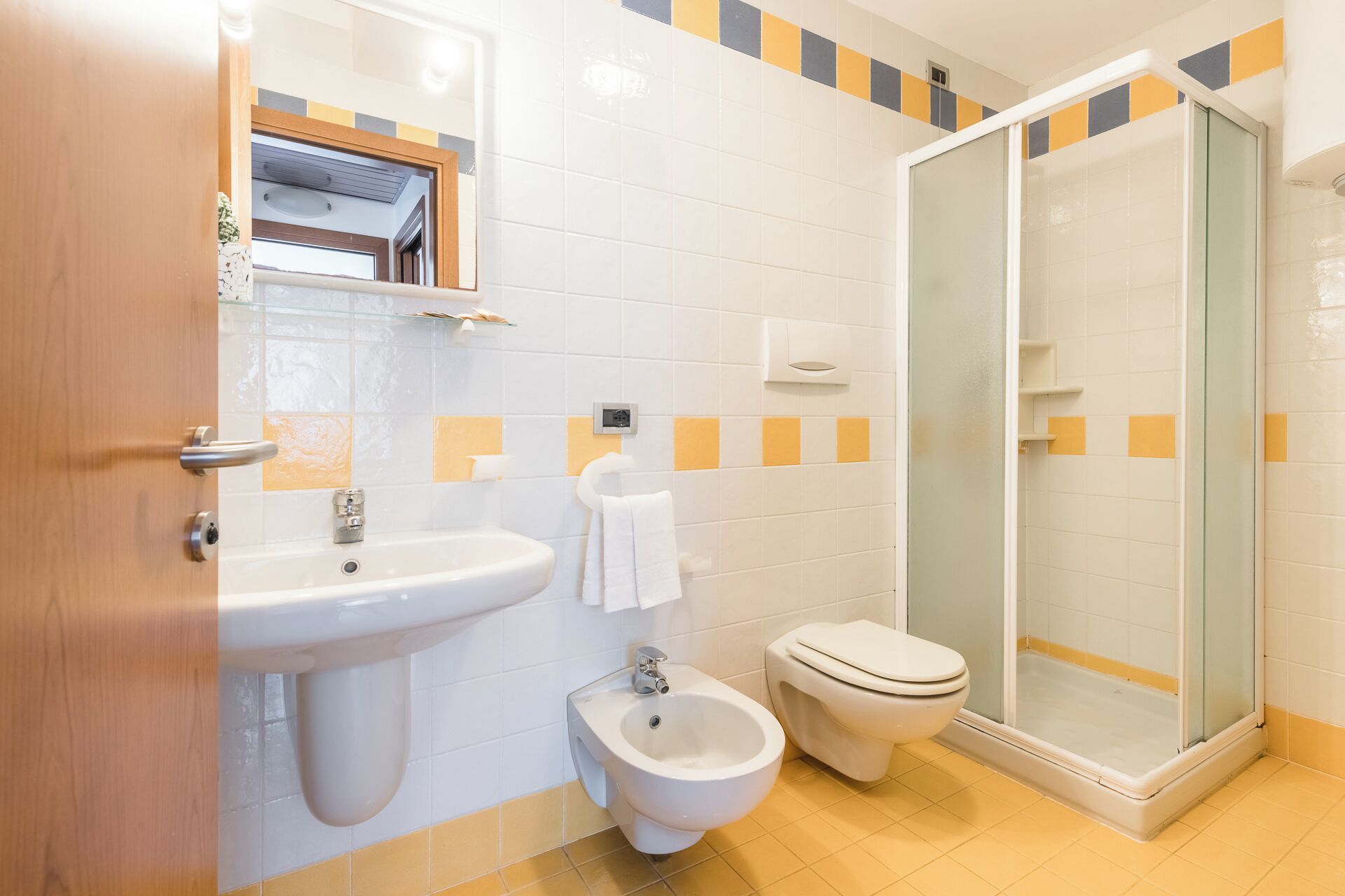 Un baño con lavamanos, bidé, inodoro y ducha con mampara de vidrio.