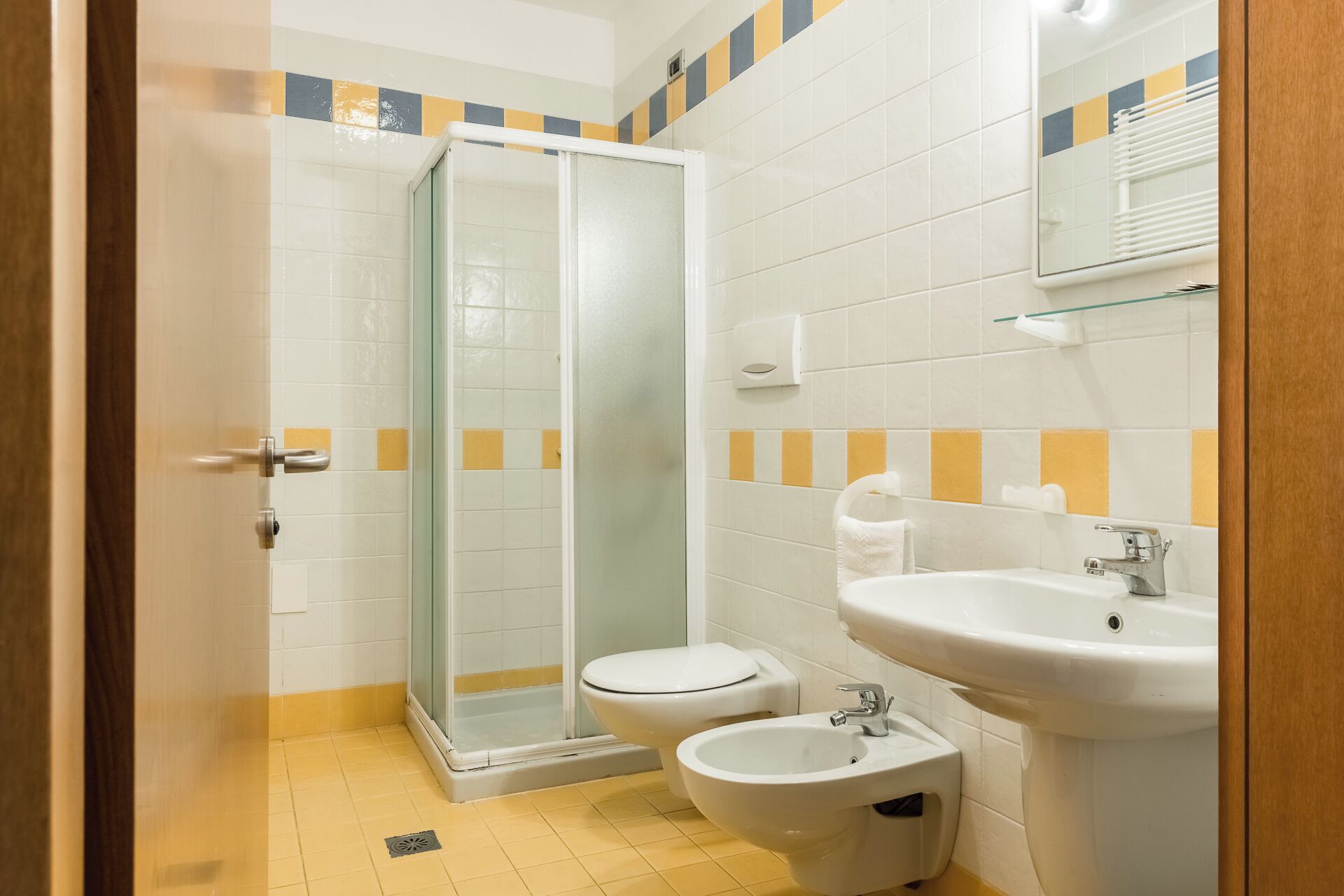 A bathroom with a glass-enclosed shower, a toilet, a bidet, and a sink.