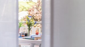 Une table avec un vase de fleurs, un verre de jus d’orange et un livre intitulé « APRÈS ».