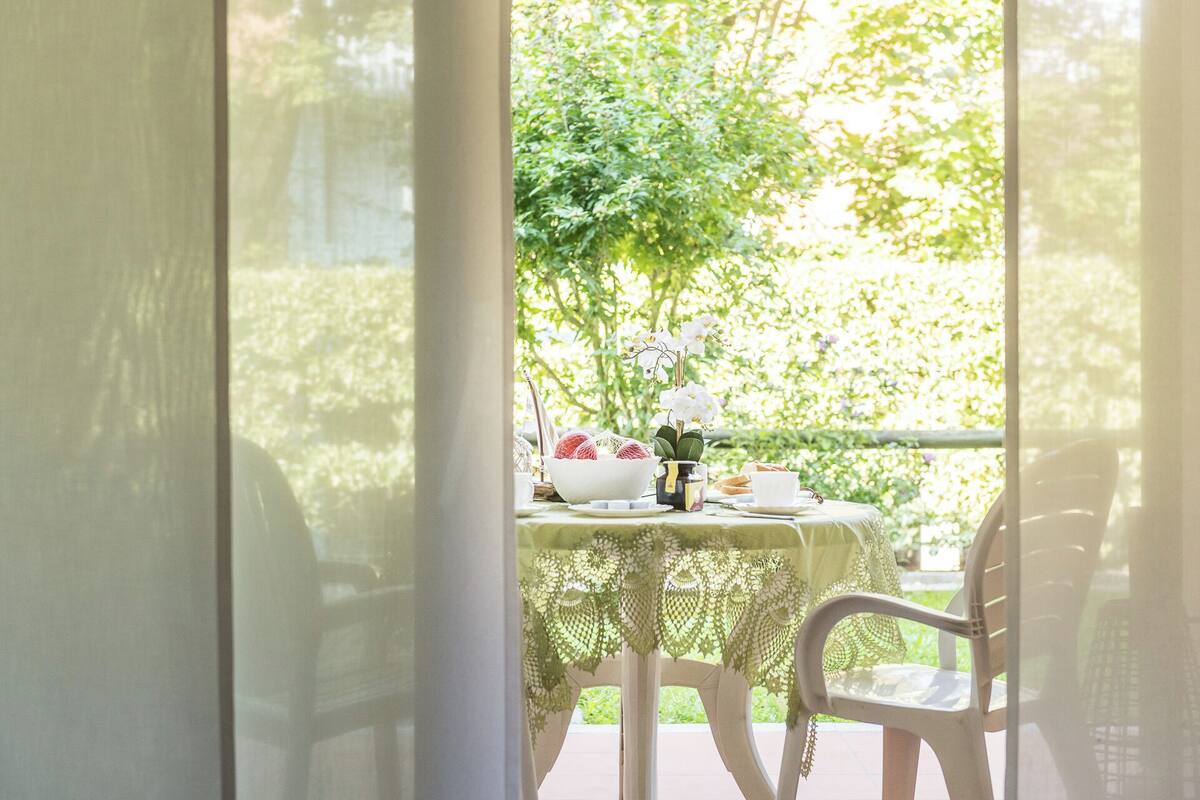 Ein Tisch, gedeckt zum Essen, mit Blick auf Grün hinter einem Fenster.