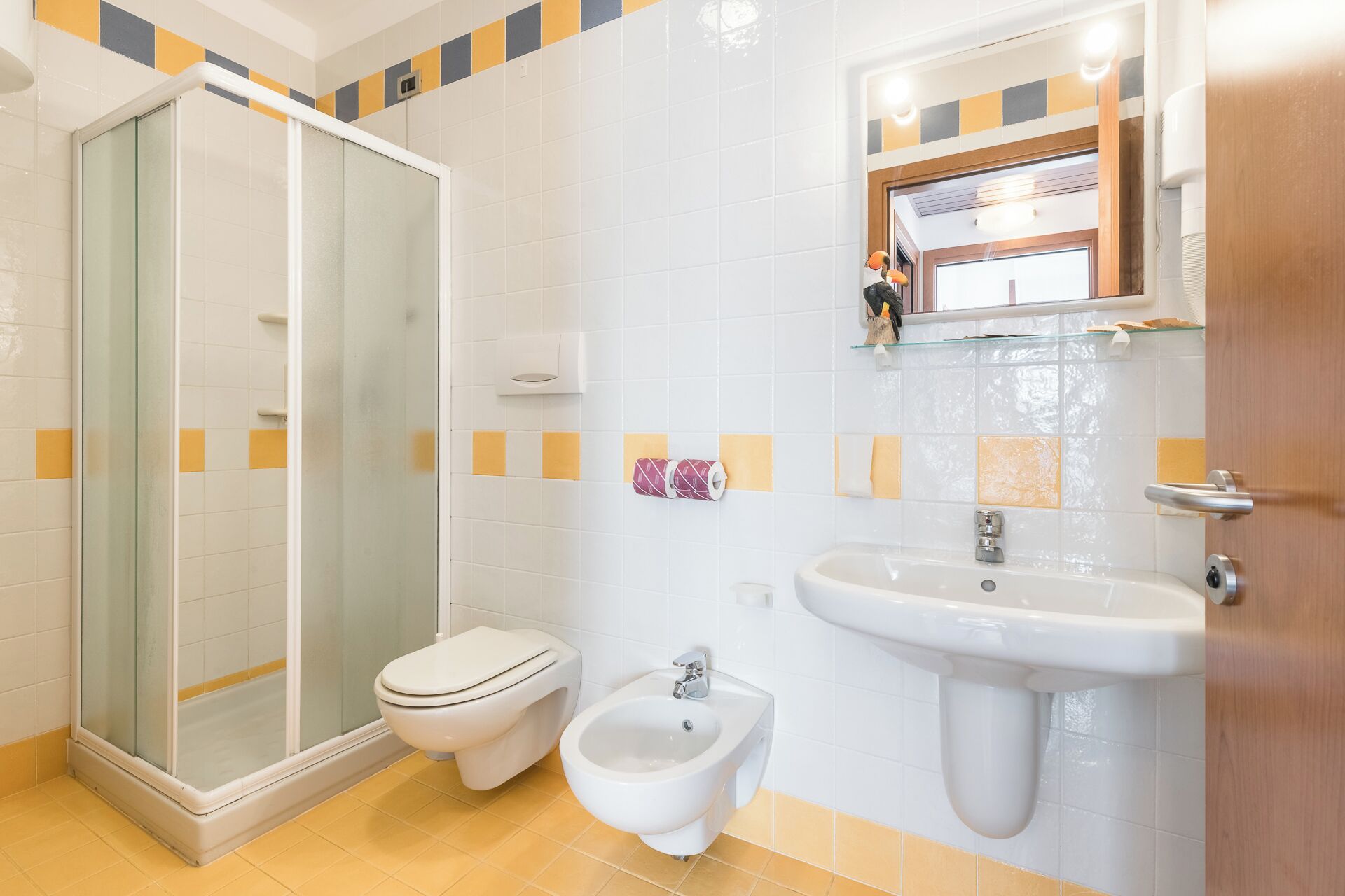A bathroom with a glass shower enclosure, a toilet, a bidet, and a sink.