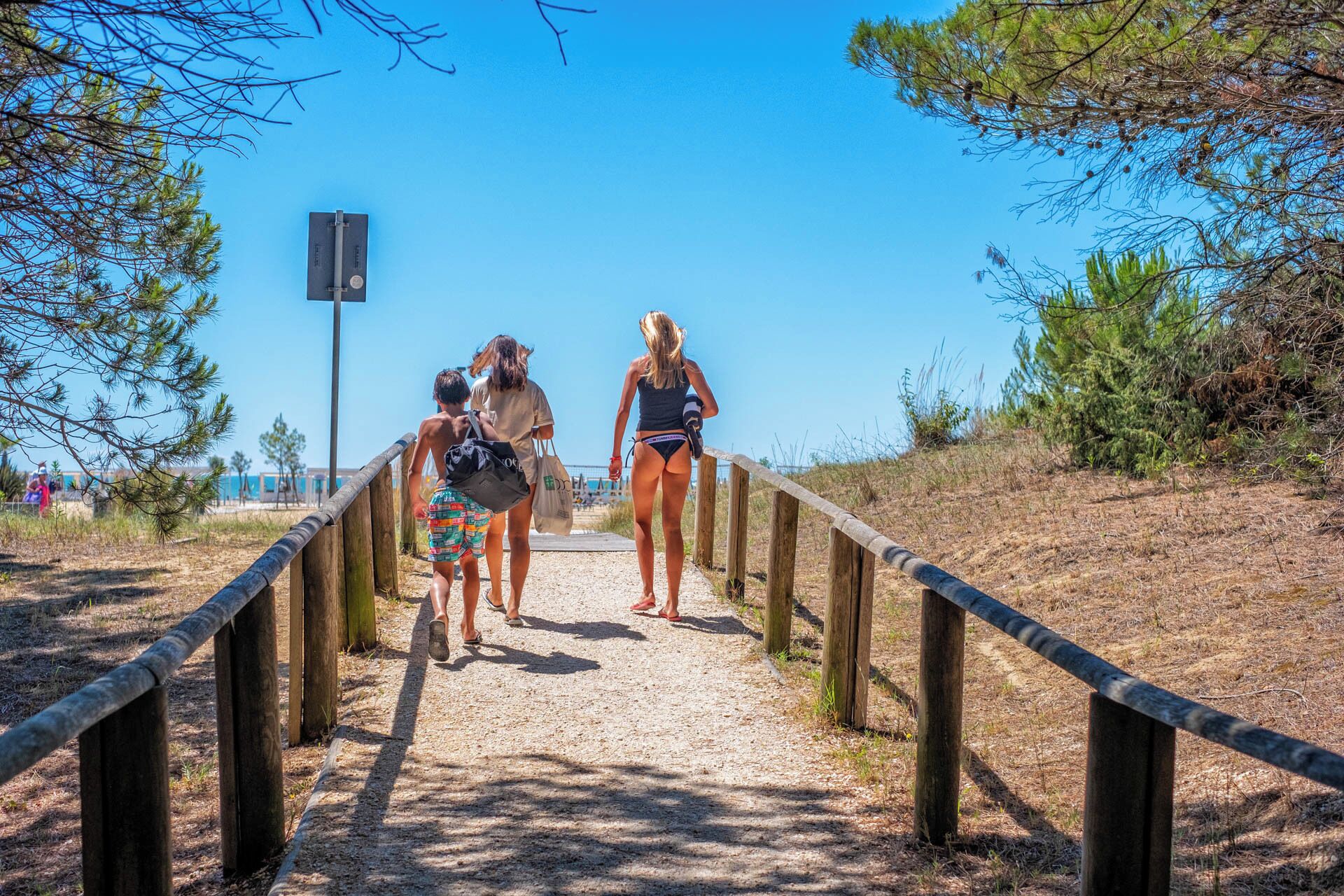 Um caminho com grades de madeira que leva a uma área de praia.