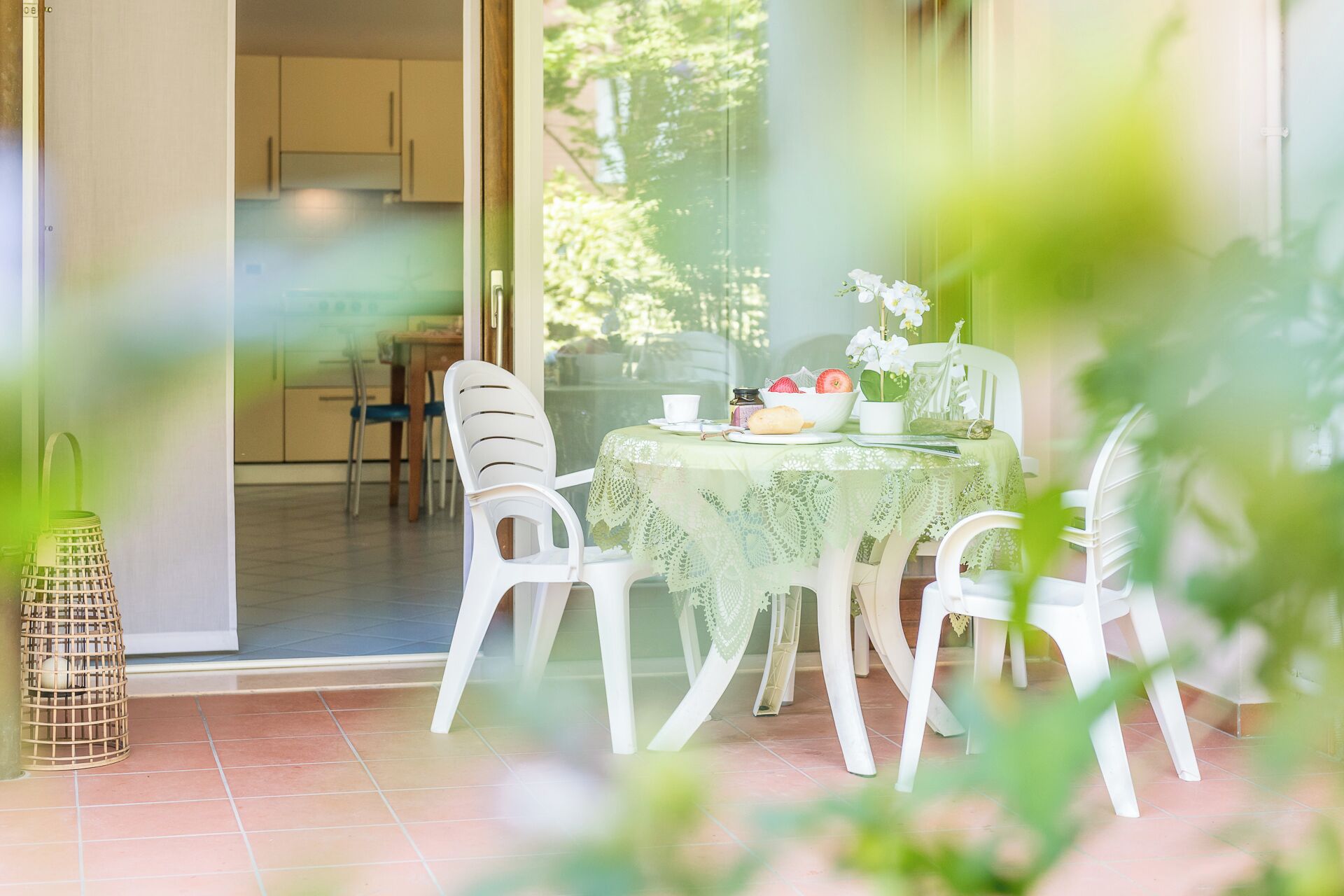Een eethoek met een tafel gedekt voor twee personen, omringd door witte stoelen, een groene tafelkleed en een schaal fruit.
