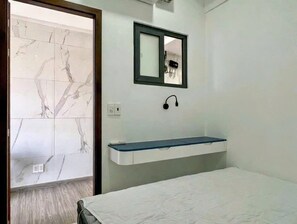 Ein Schlafzimmer mit einem Bett, einer eingebauten Ablagefläche, einem Spiegel und einer Tür zu einem Badezimmer mit Marmorfliesen.