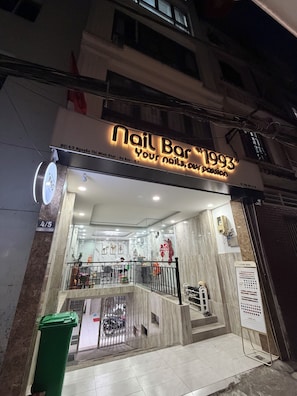 Ein Nagelstudio mit einer Neonreklame, einem Empfangstresen und einem Mülleimer vor der Tür.