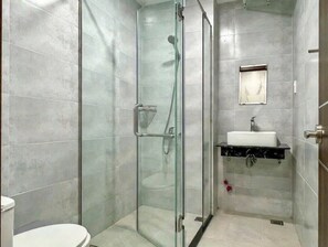 Ein Badezimmer mit einer Duschkabine, einer Toilette und einem Waschbecken mit Spiegel.
