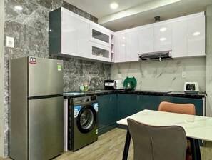 A compact kitchen with a built-in washing machine, a microwave, and a coffee maker. - Charming 1-bedroom apartment in Saigon Ward, Hochiminh city (Hồ Chí Minh)
