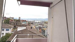 A balcony with a view of a cityscape, a table, and a chair. - Spacious studio with balcony (Vineyard 71) (Zürich)