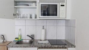 A kitchen with a microwave, sink, and dish drying rack.
