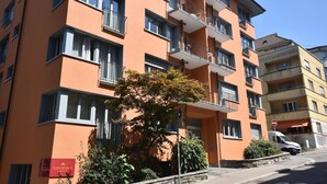 Un edificio de varios pisos con balcones, un letrero que dice 'Samatvann' y un árbol en la parte delantera.