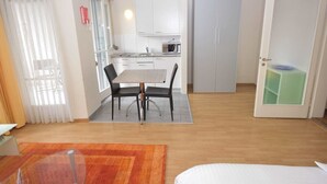 A compact living space with a dining area, kitchenette, and a door leading to another room.