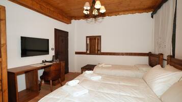 Habitación de hotel con techo de madera, televisor, escritorio, dos camas y un espejo.