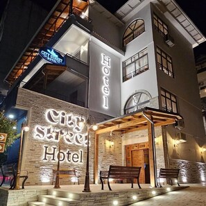 A hotel with a prominent sign reading "City Street Hotel" and a covered entrance area with benches.