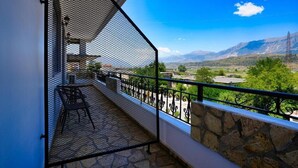 A balcony with a stone wall and metal railing, overlooking a mountainous landscape. - City Street Hotel (Gjirokaster)