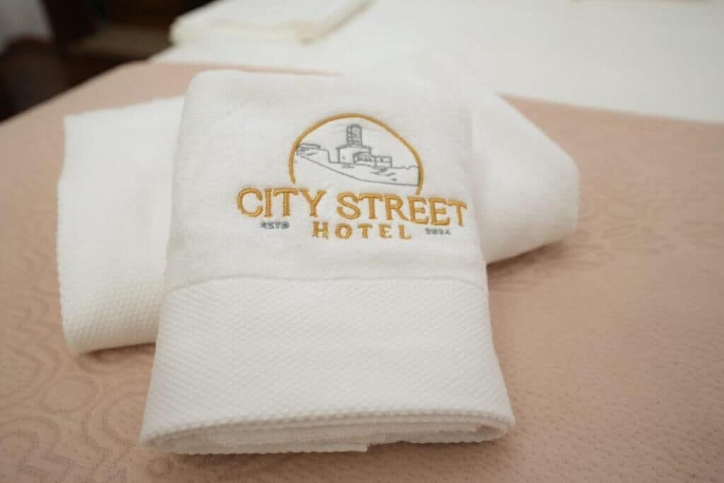 Toalla blanca doblada con el logotipo y el nombre del Hotel City Street.