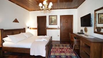 A wooden-framed bedroom with a bed, a desk, a chair, a television, and a patterned rug.