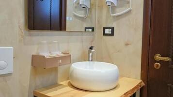 A bathroom with a wooden vanity, a round sink, a towel rack, and a mirror.