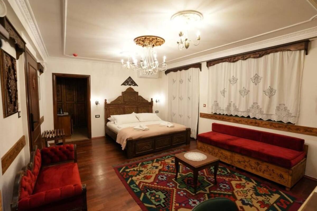 A bedroom with a wooden bed, a red sofa, a patterned rug, and a chandelier.