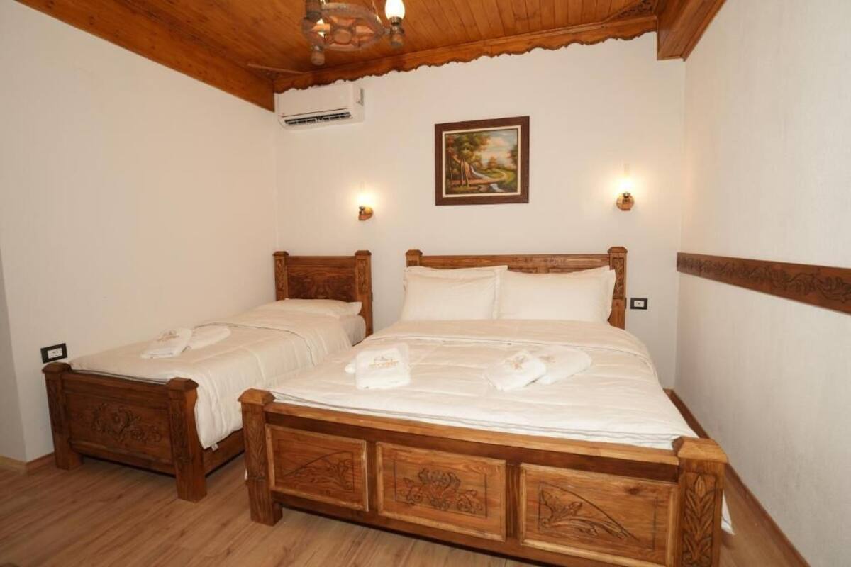 A double wooden bed with two pillows and a painting on the wall.