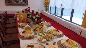 A dining area with a long table set for a meal, surrounded by chairs. - City Street Hotel (Gjirokaster)