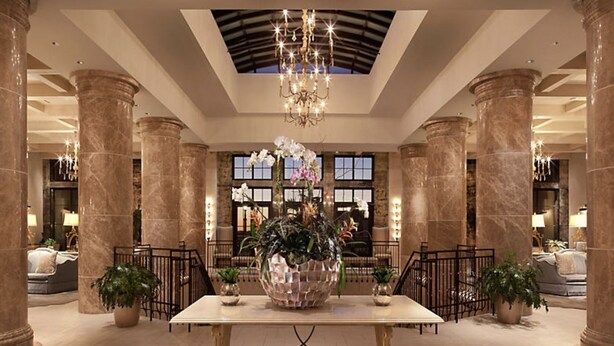 A lobby with marble columns, a chandelier, and a large floral arrangement.